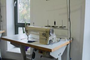 máquina de coser en la mesa de trabajo en sastrería foto