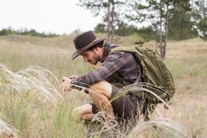 Back view of young male hiker in cowboy hat walking outdoors in summer day. Hipster traveler. photo