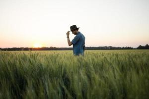 joven agricultor independiente en el campo de trigo durante la puesta de sol foto