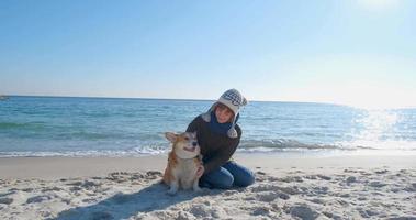 Young woman play with corgi dog on the sea beach video