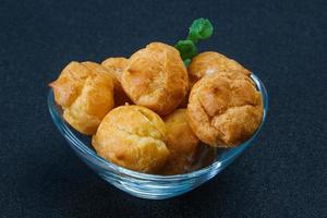 Sweet tasty profiteroles heap in the bowl photo