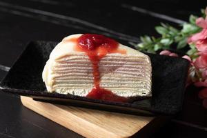 Strawberry crepe cake layered in black tones. photo