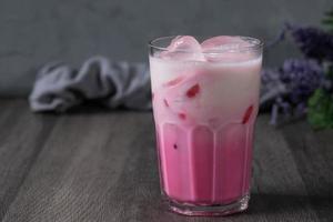 bebida fría de leche rosa fría en vidrio transparente sobre fondo gris. leche tailandesa foto