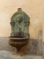 Lion head fountain in the street on an old orange wall photo