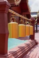 Golden bells hanging beams between red pillars. photo