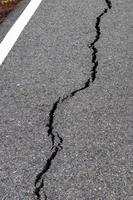 Surface cracks paved rural road near the white line. photo