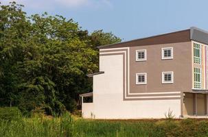 The side of the building with a forest behind the tree. photo