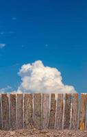 Fence from tree bark to sky clouds. photo