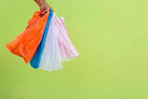 Many plastic bags in the hand against the green wall. photo