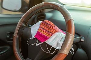 Many face masks are placed on the steering wheel inside the car. photo