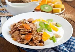 Healthy dessert with muesli and fruit in a white plate on the table photo