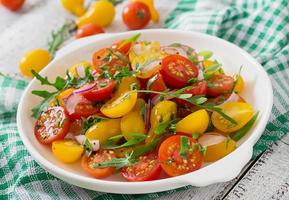 Salad of fresh cherry tomatoes with onion and arugula photo