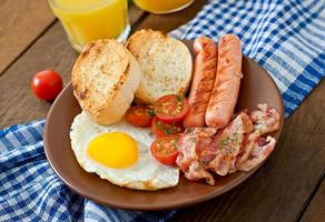 desayuno inglés - tostadas, huevo, tocino y verduras en un estilo rústico sobre fondo de madera foto