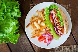 Hotdog with ketchup mustard and lettuce on wooden background. photo