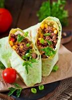 Burritos wraps with minced beef and vegetables on a wooden background photo