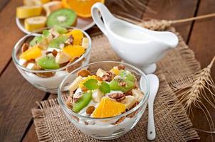 Healthy dessert with muesli and fruit in a glass bowl on the table photo