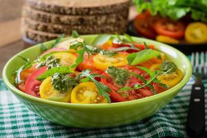 Summer tomato salad with basil, pesto and arugula photo