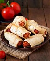 Sausage in the dough sprinkled with sesame seeds on a wooden background in rustic style photo