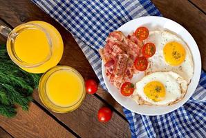 English breakfast - toast, egg, bacon and vegetables in a rustic style on wooden background photo