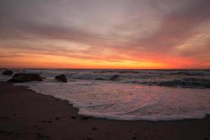 hermoso paisaje marino al amanecer, colorido cielo rosa y naranja y tormenta en el mar. foto