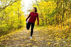 joven corredora feliz entrenando en el soleado parque de otoño foto