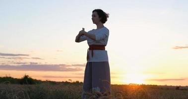 mujer practicando qigong en campos de verano con hermosa puesta de sol en el fondo foto