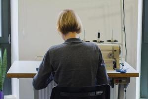 seamstress at work on the table, tailor woman work in studio with clothes photo