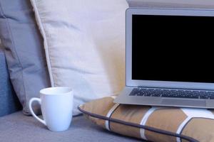 laptop in bedroom with bed, lamp and home decor background. photo