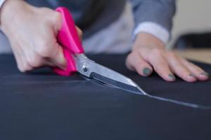 seamstress at work on the table, tailor woman work in studio with clothes photo