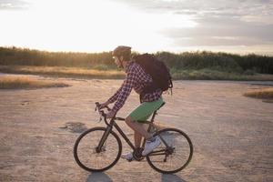 turista en bicicleta con mochilas y casco viaja en el desierto en su bicicleta de ciclocross durante la puesta de sol foto