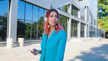 Young woman with colorful suit and pink hair drink coffee and listen to music in park photo