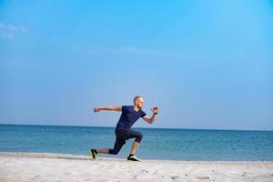 Young male athlete training in sunny day on the beach photo