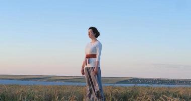 Female practicing qigong in summer fields with beautiful sunset on background photo