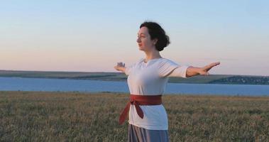 mujer practicando qigong en campos de verano con hermosa puesta de sol en el fondo foto