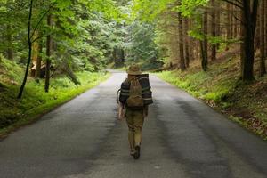joven excursionista caminando por un camino estrecho a través del bosque verde de verano foto