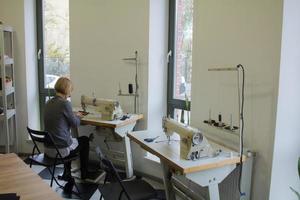 seamstress at work on the table, tailor woman work in studio with clothes photo