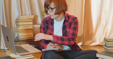 estudante jovem estudando em casa com muitos livros e laptop