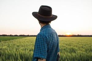 joven agricultor independiente en el campo de trigo durante la puesta de sol foto
