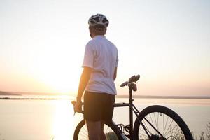 Bicycle rider on professional cyclocross bike ride downhill, pine and lake background photo