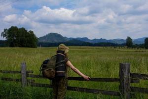 Young woman hiking on the spring meadow, mountains and forest on background photo