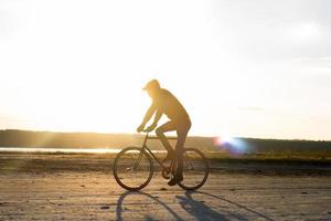 Alone rider on fixed gear road bike riding in the desert near river, hipster tourist bicycle rider pictures. photo