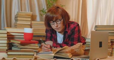 joven estudiante que estudia en casa con muchos libros y laptop