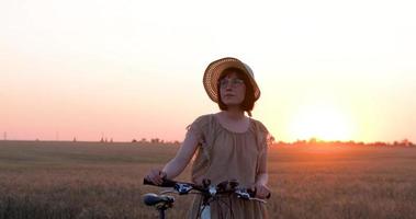 Young woman with hat ride on the bicycle in summer wheat fields video