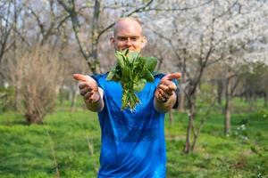 Young male athlete with fresh spinach in hands photo