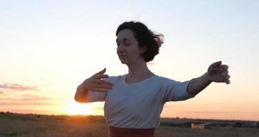 mujer practicando qigong en campos de verano con hermosa puesta de sol en el fondo foto