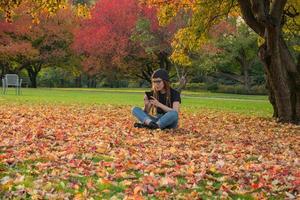 mujer joven con rastas rojas y gafas relajándose en el parque de otoño foto