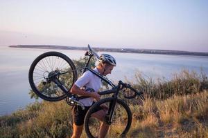 Bicycle rider on professional cyclocross bike ride downhill, pine and lake background photo