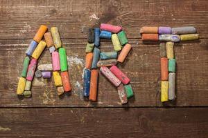 Piece of chalk with pain brushes on wooden table photo