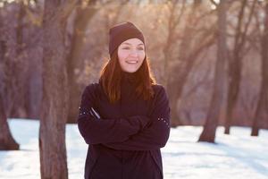 young woman athlete in black sport suit run in winter park photo