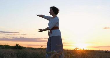 mujer practicando qigong en campos de verano con hermosa puesta de sol en el fondo foto